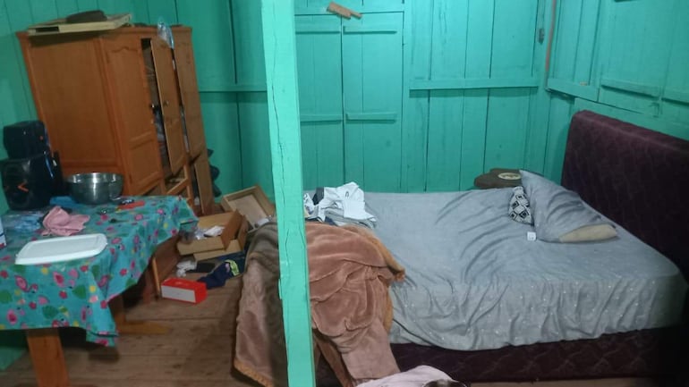 Interior de habitación sencilla con muebles de madera y objetos personales esparcidos.