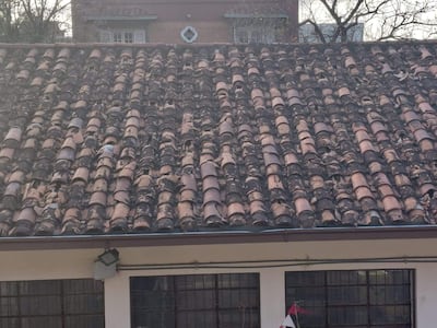 Tejado de cerámica desgastada en edificio afectado por tormenta, con tejas marrón y terracota visibles.