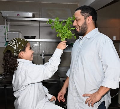 Luis Paredes. sonríe a su hija con banda verde mientras comparten un momento en la cocina en la celebración del Día del Padre.