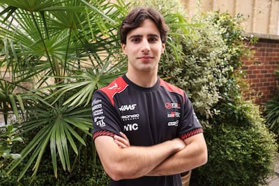 Rafael Camara en camiseta negra con detalles rojos, brazos cruzados y expresión neutral, rodeado de plantas tropicales.