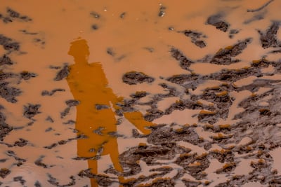 Un joven que juega cricket reflejado en el lodo tras lluvias en las afueras de Bombay, India.