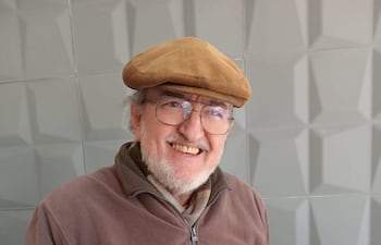 Jorge Benítez Cabral, posa con sus libros sobre las ruinas jesuíticas en un ambiente interior.