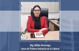Nélida Alvarenga con abrigo rojo, sentada en su escritorio con brazos cruzados y mirada directa, en ambiente de oficina.