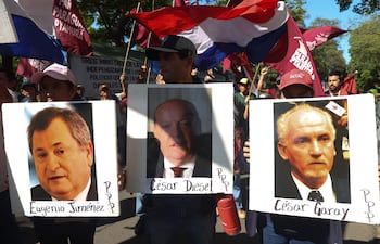 Manifestantes con carteles que muestran a algunos de los ministros de la Corte Suprema de Justicia que participaron de la reunión secreta con el presidente Santiago Peña y el titular del Partido Colorado, Horacio Cartes.