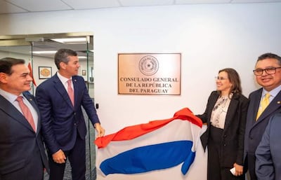 Santiago Peña y Rubén Ramírez Lezcano sonríen en la ceremonia, con banderas y documentos, en el consulado paraguayo.