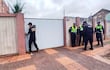 Seis agentes vestidos con uniformes oscuros frente a una puerta blanca, cuatro cerca de la pared y dos intentando abrirla.