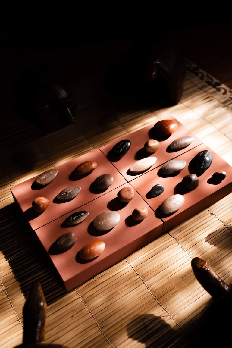 Piedras dispuestas sobre base rosada en un espacio de exhibición con muebles de madera.