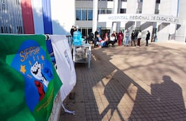 Grupo de personas con bandera del SIFIPSAP, algunos sentados y otros de pie, en un ambiente exterior bien iluminado.