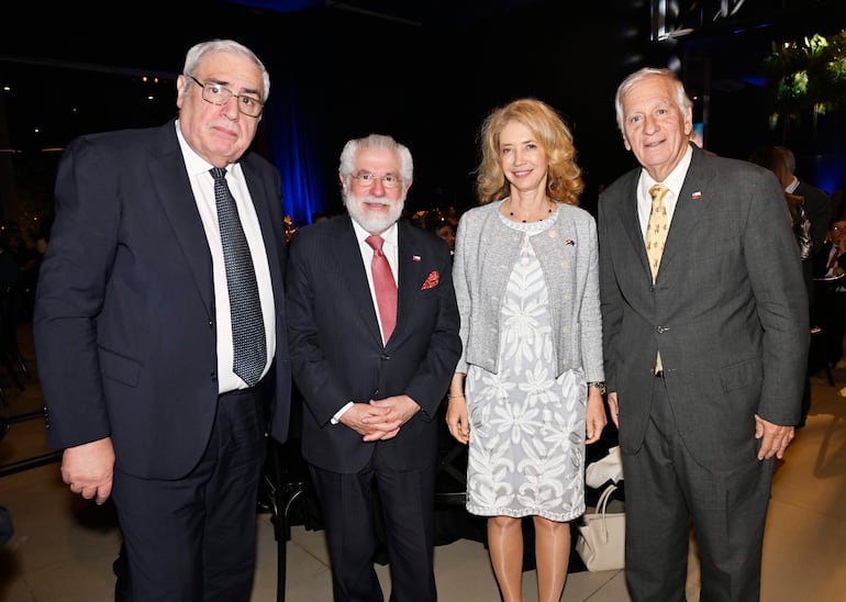 Francisco Benavente con traje oscuro, Francisco Sanfurgo en traje negro con corbata roja y Katja Afheldt con vestido blanco sonríen en la cena.