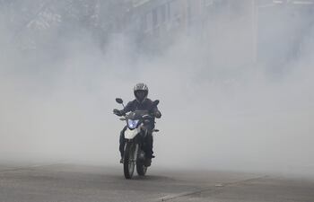 Un hombre en motocicleta transita por una avenida cubierta de humo, este martes en Tegucigalpa (Honduras).