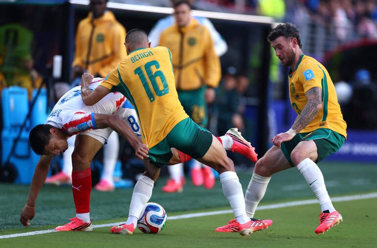 Diego Gómez #8 de Paraguay disputa el balón contra Aziz Behich y Aiden O'Neill de Australia durante el partido del Grupo D de la Copa Mundial de la FIFA 2026 entre Paraguay y Australia en el San Francisco Bay Area Stadium.