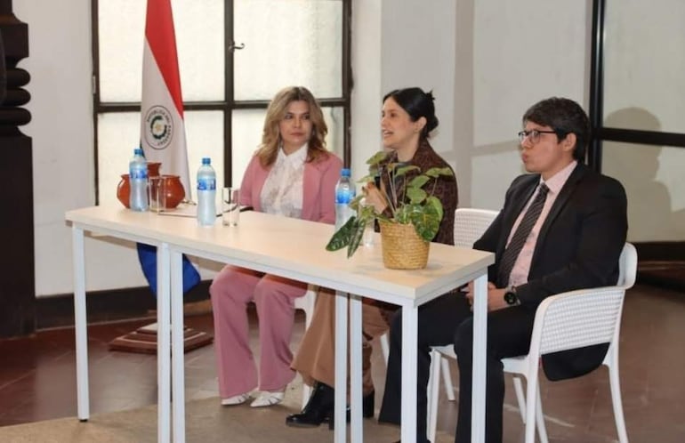 Natalia Fuster en traje oscuro conversa mientras otros tres escuchan atentamente en mesa blanca con decoración mínima.