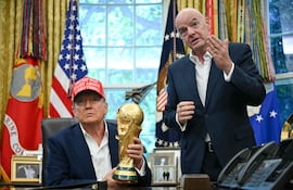 El presidente de Estados Unidos, Donald Trump, acompañado por el presidente de la FIFA, Gianni Infantino (derecha), sostiene el trofeo de la Copa Mundial mientras realiza un anuncio en el Despacho Oval de la Casa Blanca en Washington, D.C., el 22 de agosto de 2025.