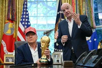 El presidente de Estados Unidos, Donald Trump, acompañado por el presidente de la FIFA, Gianni Infantino (derecha), sostiene el trofeo de la Copa Mundial mientras realiza un anuncio en el Despacho Oval de la Casa Blanca en Washington, D.C., el 22 de agosto de 2025.