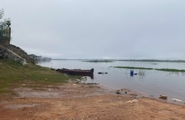 Bote de madera sobre la orilla del río Paraguay, rodeado de vegetación y un paisaje acuático nublado.