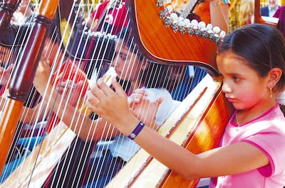Un grupo de niños ejecuta el arpa paraguaya.