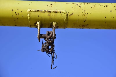 Estructura metálica amarilla oxidada cuelga de una barra bajo un cielo azul despejado, reflejando abandono en el parque.
