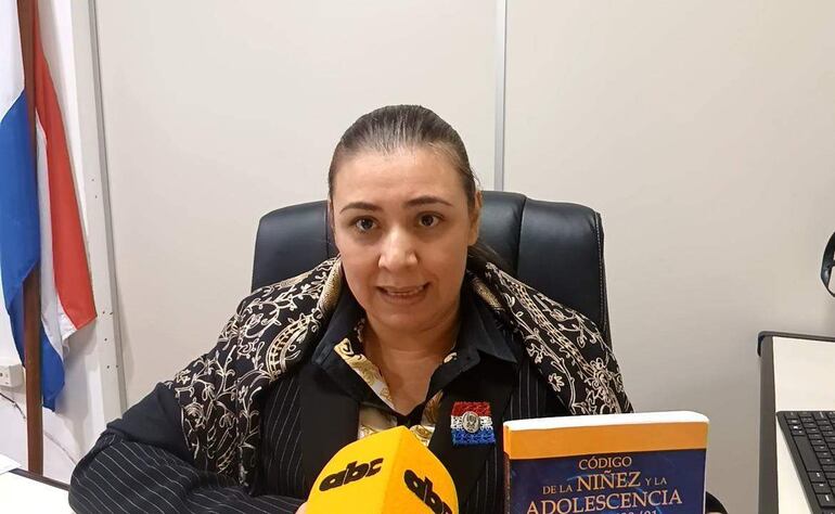 Liz Gonçalves en oficina, sosteniendo el libro 'Código de la Niñez y Adolescencia'