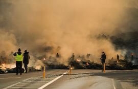Imagen ilustrativa: trabajadores de los medios de comunicación junto a un flujo de lava durante una erupción volcánica cerca de Grindavik, península de Reykjanes, Islandia.