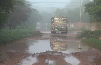 Bus de la Línea 2 avanza por carretera cubierta de barro, con charcos de agua y vegetación a un costado.