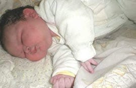 Brígida Benítez, bebé de 8 kilos, duerme tranquila sobre mantas blancas y amarillas con cabello corto y oscuro.