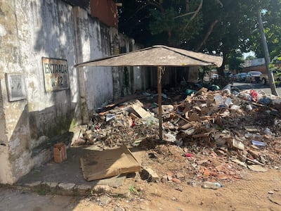 Entorno descuidado con toldo cubriendo basura y cartel deteriorado, en un ambiente urbano desordenado.