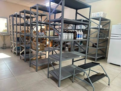 Interior de un depósito con estanterías grises cargadas de cajas y frascos, sin personas visibles.