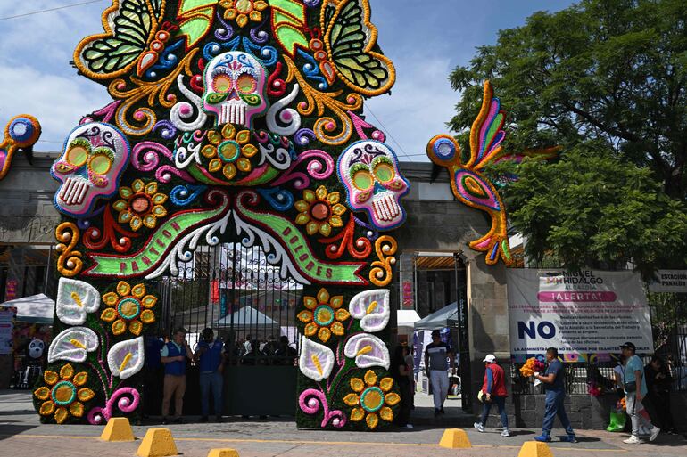 Personas llegan cargando flores para visitar las tumbas de sus seres queridos en el Panteón de Dolores como parte de las celebraciones del Día de Muertos en la Ciudad de México, el 1 de noviembre de 2025.
