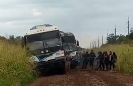 Grupo de pasajeros bajan para ayudar a mover el colectivo, atrapado en el barro