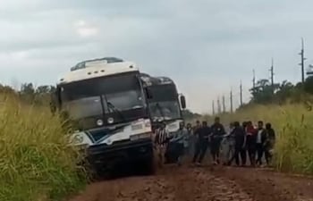 Grupo de pasajeros bajan para ayudar a mover el colectivo, atrapado en el barro