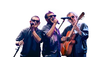 Músicos de Los Nocheros en el escenario, con gafas de sol y micrófonos, recreando una atmósfera de concierto musical.