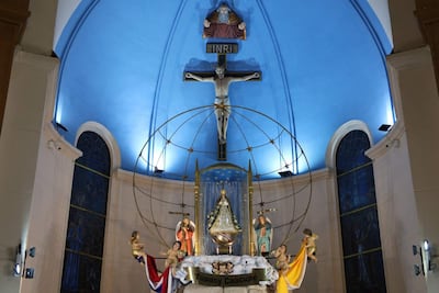 Altar en la basílica de Caacupé con figura de la Virgen rodeada de ángeles y fondo azul iluminado.