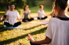 Un grupo de mujeres jóvenes practica yoga al aire libre.