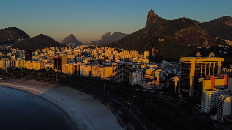 Fotografía que muestra edificios alrededor de la cala de Botafogo con el monumento de Cristo Redentor, Pedra da Gávea y Morro Dois Irmãos en el fondo durante un amanecer en Río de Janeiro (Brasil). 