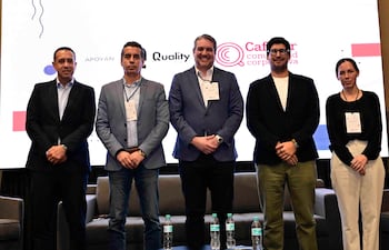Ulises Cabral en traje negro, rodeado de cuatro panelistas, todos con diversas vestimentas y expresiones serenas en un fondo de logos.