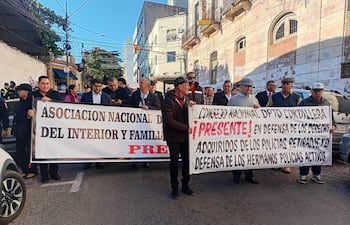 Protesta de policías retirados en Asunción, sosteniendo pancartas y vestidos con abrigos, expresando angustia y solidaridad.