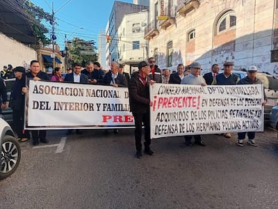 Protesta de policías retirados en Asunción, sosteniendo pancartas y vestidos con abrigos, expresando angustia y solidaridad.