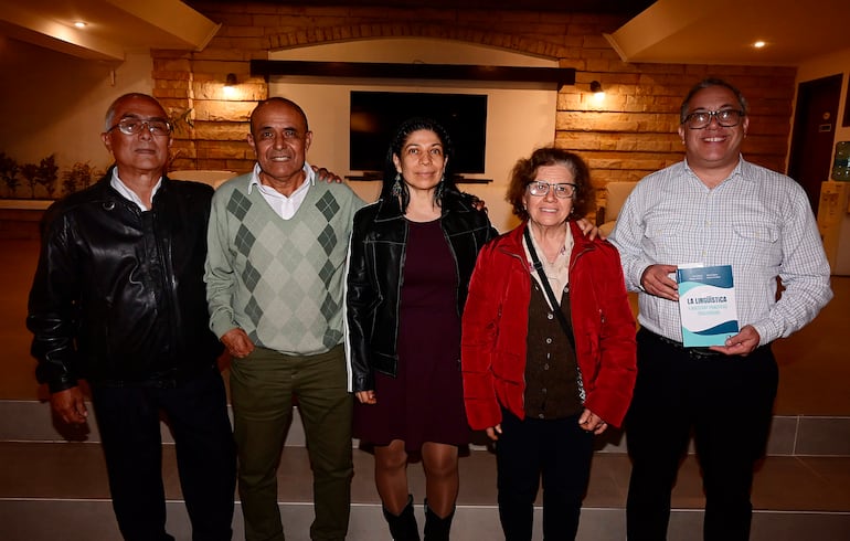 Mujer de chaqueta negra, hombre con gafas y chaqueta de cuero negro, mujer en chaqueta roja, hombre con camisa de cuadros, sonrientes en evento.