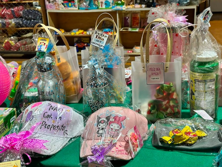 Exhibición de regalos envueltos en celofán y cintas en mesa verde, sin personas visibles, celebrando el Día de la Amiga.