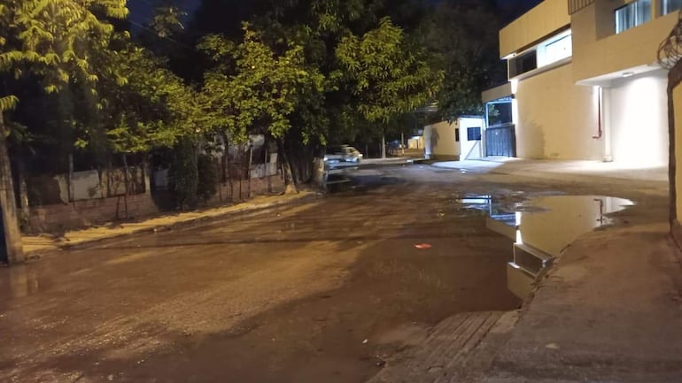 Calle del barrio Virgen de la Asunción con pavimento destrozado y charcos de agua acumulada.