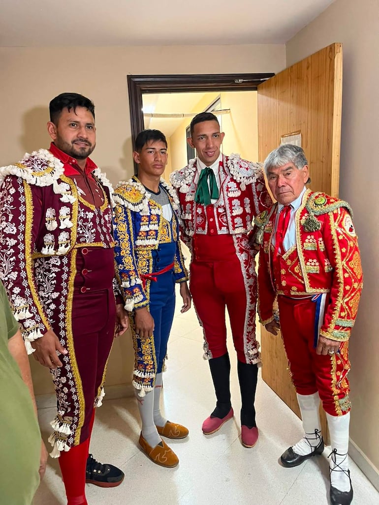 Cuatro toreros con trajes de luces en un vestidor, posando con expresiones tranquilas y felices.