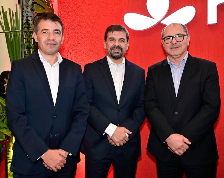 Tres hombres de pie en trajes formales, con fondo rojo, posando para la foto en un evento de MAPFRE.