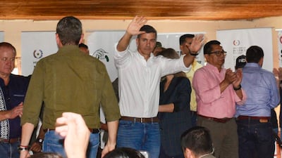 Santiago Peña en camisa blanca, levantando la mano mientras varios asistentes aplauden en un evento formal.