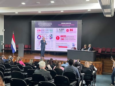 Enrique Riera en conferencia, gesticulando mientras presenta estadísticas sobre monitoreo electrónico frente a una audiencia atenta.
