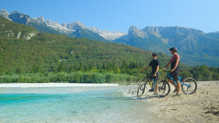 Dos hombres en bicicleta observan el paisaje del valle del río Soca, Eslovenia.