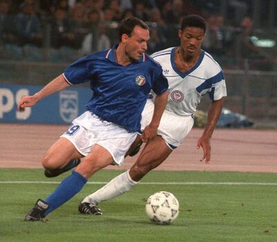 (FILES) Italian forward Salvatore Schillaci (L) tries to control the ball under pressure from US defender Jimmy Banks during the World Cup first round soccer match between Italy and the United States 14 June 1990 in Rome. Former Italy striker Salvatore "Toto" Schillaci, most famous for being top scorer at the 1990 World Cup, died on September 18, 2024 at the age of 59. Juventus were among Italy's football clubs to pay tribute to Schillaci, who became an icon for his unexpected goalscoring exploits at his country's home World Cup, simply saying "Ciao Toto" on social media with a picture of him in a Juve shirt. (Photo by STAFF / AFP)