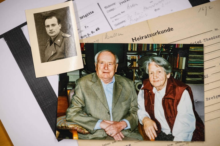 Esta fotografía, tomada el 2 de junio de 2026, muestra una imagen (centro) de los abuelos del profesor alemán Felix Puelm, Paul y Brigitte, una pequeña fotografía (arriba a la izquierda) de Paul con uniforme militar, su certificado de matrimonio (derecha) y, en la parte inferior sobre papel blanco, una copia del carné de afiliación al Partido Nacionalsocialista Obrero Alemán (NSDAP) de su abuela Brigitte, hallado en una base de datos en línea publicada por el semanario alemán Die Zeit. 