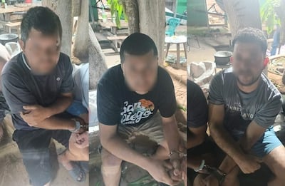 Tres hombres esposados, sentados en un entorno al aire libre con expresión seria y manos cruzadas, rodeados de árboles y mobiliario informal.