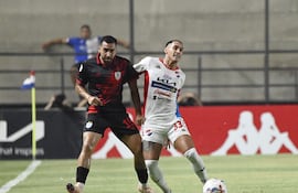 El lateral de Ameliano Jesús Abel Paredes intenta anticipar la maniobra ofensiva del extremo de Nacional Orlando Gaona Lugo.