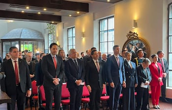 Santiago Peña en traje oscuro, rodeado de cinco personas bien vestidas en un salón con luz natural y decoración formal.
